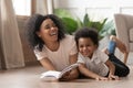 African mom reading book laughing with child son at home Royalty Free Stock Photo