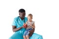 a caring African-American pediatrician treats a little girl patient with an apple and talks about healthy eating. The