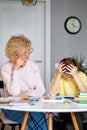 Caring beautiful grandma sit with upset daughter while doing homework, drawing