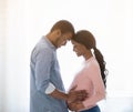 Caring black man hugging his pregnant wife`s belly near window indoors, side view Royalty Free Stock Photo