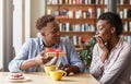 Caring boyfriend surprising his girlfriend with unexpected gift at coffee shop