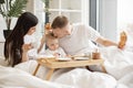 Parents with baby having meal in bed of studio apartment Royalty Free Stock Photo