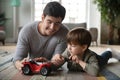 Caring dad play with cars with small preschooler son