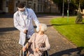 Caring doctor rolling a wheelchair with an elderly woman