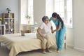 Female caregiver who cares for an elderly woman in a nursing home helps her get out of bed. Royalty Free Stock Photo