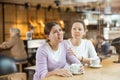 Empathetic woman comforting upset younger sister in cafe