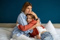 Caring empathic young mom affectionately cuddling calming upset depressed teen daughter.