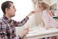 Caring father feeds his lovely daughter with delicious food using a spoon in a cozy home. Royalty Free Stock Photo