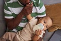 Caring father kissing tiny hand of baby son and giving him formula in bottle Royalty Free Stock Photo