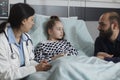 Caring father sitting next to sick daughter resting in hospital pediatric ward Royalty Free Stock Photo