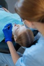 Caring female dentist checking patients upper teeth