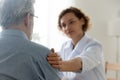 Caring female doctor comfort senior male patient at consultation Royalty Free Stock Photo