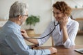 Caring female doctor listen to elderly patient heartbeat Royalty Free Stock Photo