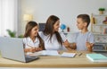 Caring and friendly young mother helps her children to complete their school homework. Royalty Free Stock Photo