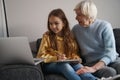 Lovely child and her grandma looking at laptop screen