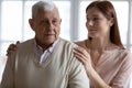 Caring grownup granddaughter express sympathy stroking elderly grandfather