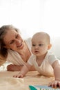 A caring joyful grandmother plays with her little grandson lying on the floor in a bright children's room. Various Royalty Free Stock Photo