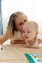 Caring joyful mother plays with her little child, lying on the floor in a bright children& x27;s room. Various toys, a Royalty Free Stock Photo