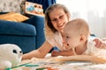 Caring joyful mother plays with her little child, lying on the floor in a bright children's room. Various toys, a Royalty Free Stock Photo