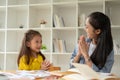 A caring Asian female teacher is clapping her hands with a little girl, feeling proud of her student Royalty Free Stock Photo