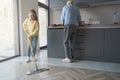 Caring little girl cleaning the floor while assisting her grandma