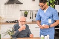 Young healthcare worker observing a pensioner swallowing down a medication Royalty Free Stock Photo