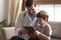 Caring male pediatrician watch video on pad with little patient Royalty Free Stock Photo