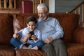 Mature grandfather and little grandson have fun using cellphone