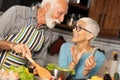 Caring mature husband preparing lunch for happy grateful smiling aged wife