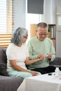 Caring mature man checking blood sugar of his diabetic wife at home. Elderly healthcare concept Royalty Free Stock Photo