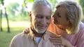 Caring mature wife flirting with handsome husband in park, whispering compliment