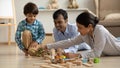 Caring mixed race parents building dino park with preschooler son