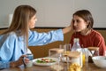 Caring mom gentle touch head teen girl sitting at table on morning breakfast. Trusting relationship