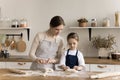 Caring mom teaching cute toddler girl in apron to cook Royalty Free Stock Photo