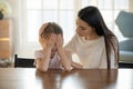 Caring mother calming and hugging upset little daughter