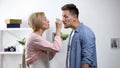 Caring mother feeding adult son with spoon, negative side of overprotection Royalty Free Stock Photo