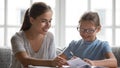 Caring mother help daughter with school assignment at home