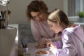 Caring mother helping to teenage daughter with school homework Royalty Free Stock Photo