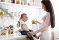 Caring mother offering fresh green apple to her infant at kitchen Royalty Free Stock Photo