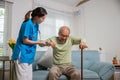 Caring nurse helping supporting senior disabled man to stand up with walking stick Royalty Free Stock Photo