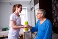 Caring nurse holding a hand of a senior man occupant in a nursing home room