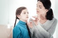 Caring pleasant mother sitting and treating her daughter.