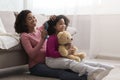 Caring pregnant african mom combing her little daughter`s hair at home Royalty Free Stock Photo