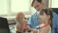 Caring professional male pediatrician playing with a small child in the office. little girl plays with teddy bear toy Royalty Free Stock Photo