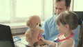 Caring professional male pediatrician playing with a small child in the office. little girl plays with teddy bear toy Royalty Free Stock Photo