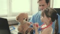 Caring professional male pediatrician playing with a small child in the office. little girl plays with teddy bear toy Royalty Free Stock Photo