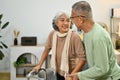 Caring senior man helping his wife walking with walker for rehabilitation and therapy