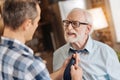 Caring son tying the tie of his senior father