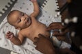 Caring young black father tickling tummy of his newborn baby . Fatherhood and multiracial family