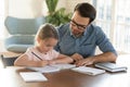 Caring young father helping little daughter with homework.